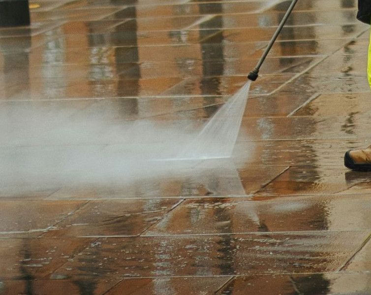 a man in a yellow jacket is using a pressure washer